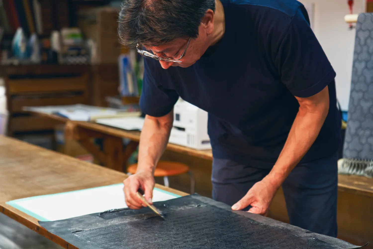 彫刻された型紙を生地に当て、染色を施す「型付け捺染」の工程